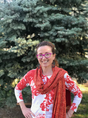 Therese Williams standing outside in front of a tree smiling.