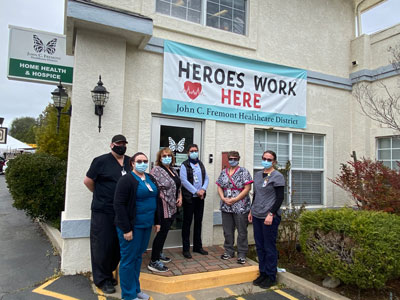 John C. Fremont Home Health & Hospice building with some of the staff standing in front of the front door. There is five females and one male. They each are wearing a mask.