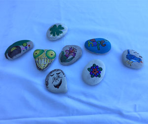 Picture of eight rocks that are each hand painted differently.
