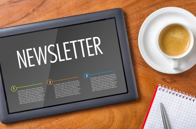 Picture of a tablet that says:" Newsletter" and a cup of coffee sitting next to it with a little bit of a notebook and pen in the image at the bottom.