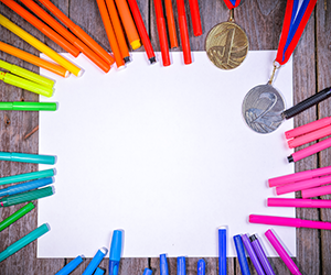 Picture of colored markers surrounding a white sheet of paper.